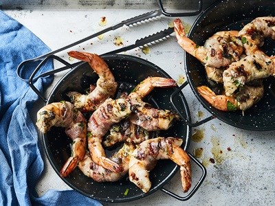 Grilled prawns wrapped in bacon with herbs and lemon